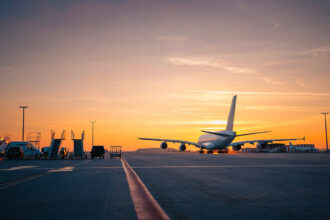 Wide shot of an airport runway glowing under a golden sunset, capturing the mood of travellers searching for the cheapest flight to the Philippines as planes move across the tarmac.