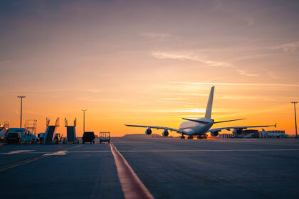 Wide shot of an airport runway glowing under a golden sunset, capturing the mood of travellers searching for the cheapest flight to the Philippines as planes move across the tarmac.