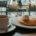 Breakfast with pancakes and coffee at a cafe with harbor view, similar to cozy brunch spots at the best restaurants in Manila.