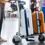 Woman walking through a busy airport terminal carrying multiple suitcases, demonstrating Philippine Airlines baggage allowance for checked and carry-on bags