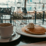 Breakfast with pancakes and coffee in cafe with harbor view in Manila, Philippines. Cozy morning scene with food and blurred city background. Perfect for travel, lifestyle, and editorial use.