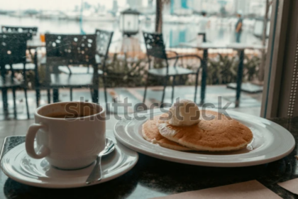 Breakfast with pancakes and coffee in cafe with harbor view in Manila, Philippines. Cozy morning scene with food and blurred city background. Perfect for travel, lifestyle, and editorial use.