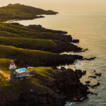 Batanes tourist attraction featuring green hills and beach at sunset in Batanes, Philippines