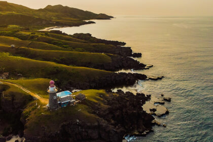 Batanes tourist attraction featuring green hills and beach at sunset in Batanes, Philippines