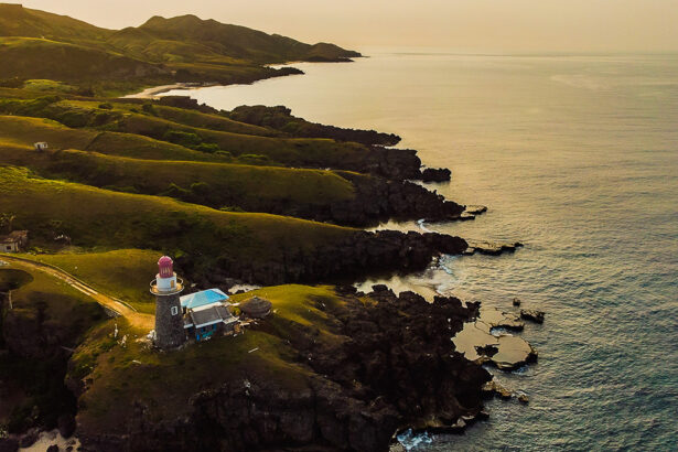 Batanes tourist attraction featuring green hills and beach at sunset in Batanes, Philippines