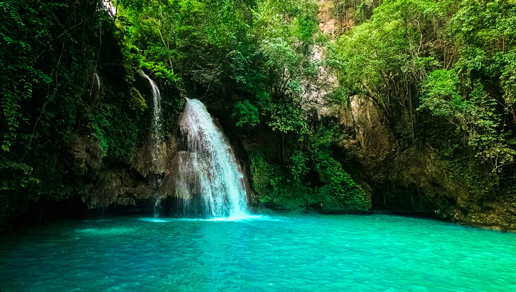Kawasan Waterfall, one of the iconic waterfalls in the Philippines, cascading through a mountain gorge in a lush tropical jungle in Cebu.
