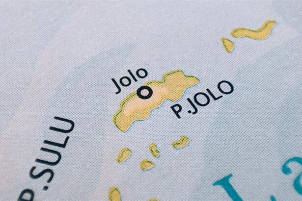 A close-up photograph of a printed map showing Jolo Island, labeled as "P. JOLO," with a black circle indicating the location of the town of Jolo within the Sulu Archipelago.