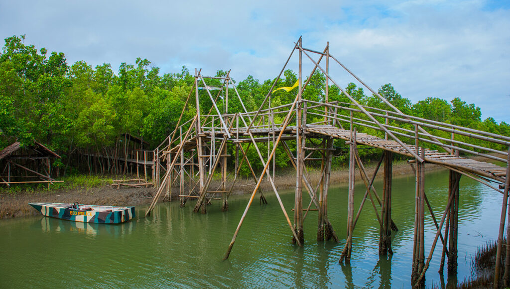 Scenic wooden bridge and boat along the river at Bakhawan Eco-Park, one of the top nature focused things to do in Kalibo for eco-tourists