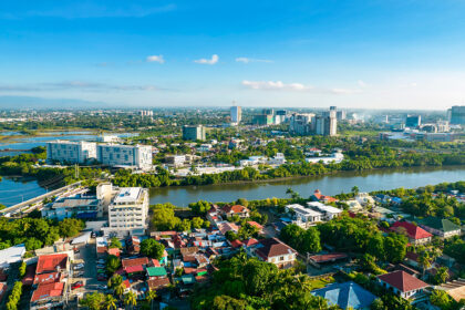 An aerial high-angle view of the Iloilo City skyline featuring the Iloilo River snaking through the cityscape, with modern high-rise buildings and residential areas under a clear blue sky—a perfect starting point for travelers looking for things to do in Iloilo City.