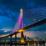 Nighttime view of the Cebu-Cordova Link Expressway (CCLEX) bridge illuminated in purple under a clear sky, typical of the calm Philippines weather in March.