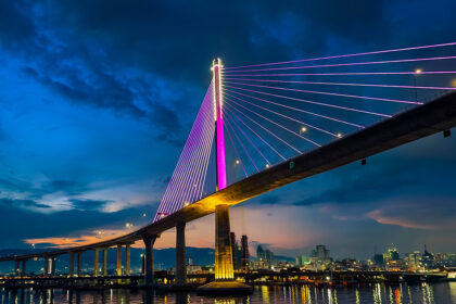 Nighttime view of the Cebu-Cordova Link Expressway (CCLEX) bridge illuminated in purple under a clear sky, typical of the calm Philippines weather in March.