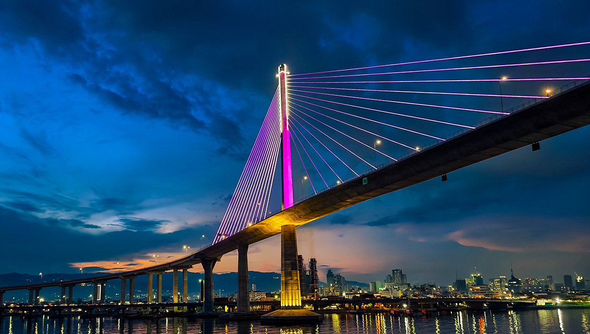 Nighttime view of the Cebu-Cordova Link Expressway (CCLEX) bridge illuminated in purple under a clear sky, typical of the calm Philippines weather in March.