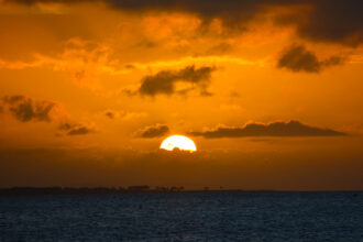 A dramatic tropical sunset over the ocean, reflecting the hazy and humid conditions typical of Philippines weather May as the monsoon season approaches.