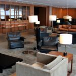 A luxury Manila airport lounge featuring mid-century modern leather armchairs, warm wood paneling, and ambient designer lighting for premium passenger comfort.
