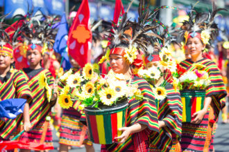 A vibrant cultural parade showcasing the festive spirit of Philippines weather May, with dancers in colorful costumes and sunflowers under a bright, sunny sky.