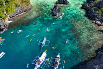 Aerial view of outrigger boats and kayakers in a turquoise lagoon, a popular stop when spending 2 weeks in Philippines exploring Palawan.