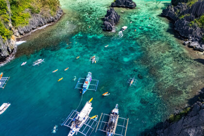 Aerial view of outrigger boats and kayakers in a turquoise lagoon, a popular stop when spending 2 weeks in Philippines exploring Palawan.