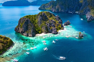 Aerial view of a Shimizu Island near El Nido and outrigger boats, one of the top things to do in Palawan for island hoppers.