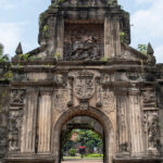 The iconic stone entrance of Fort Santiago in Intramuros, showcasing Spanish-era architecture and historical carvings found on city-based day trips from Manila.