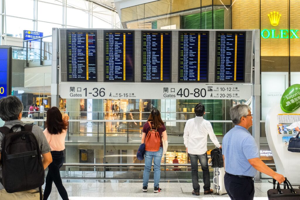 Passengers checking an airport departure board while planning cheap domestic flights Philippines