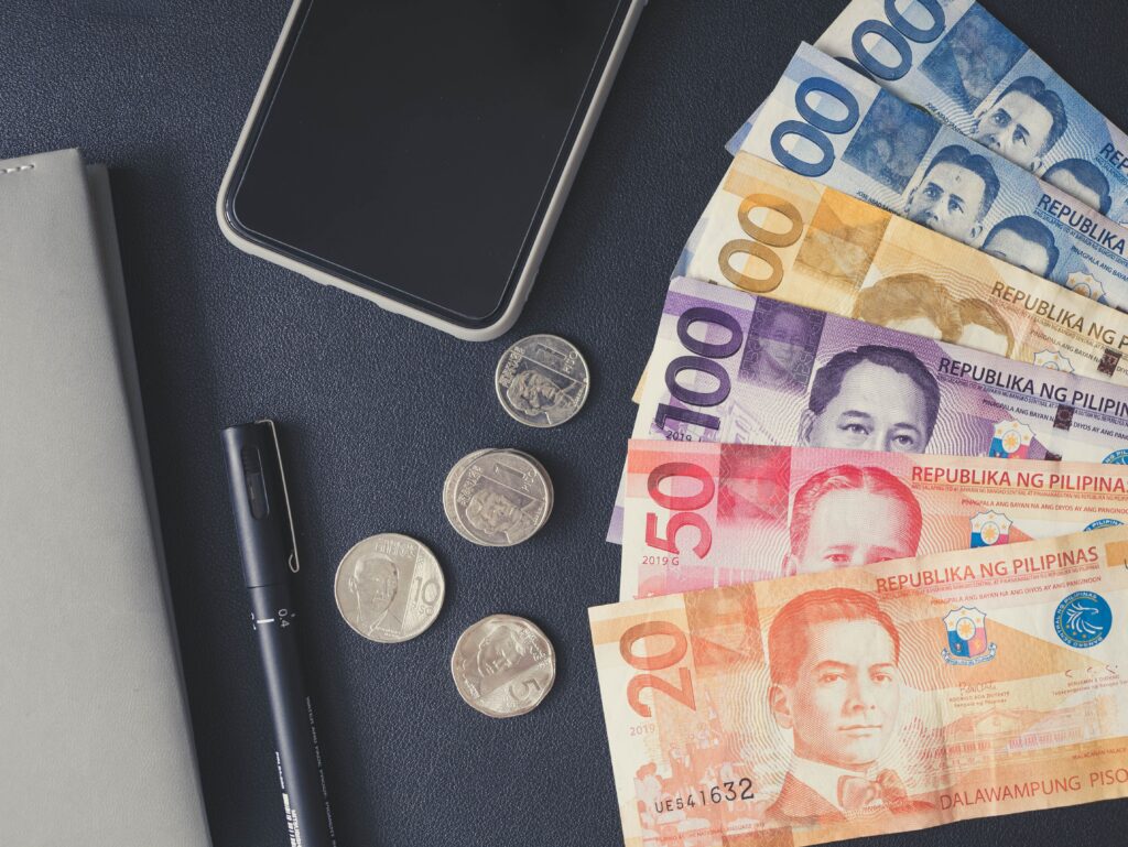 Philippines Currency banknotes and coins displayed on a black surface