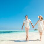 Couple walking hand in hand on a sandy beach during a romantic Philippines honeymoon
