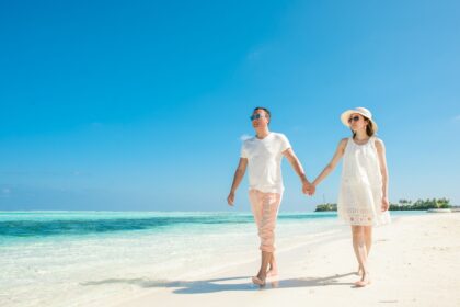Couple walking hand in hand on a sandy beach during a romantic Philippines honeymoon