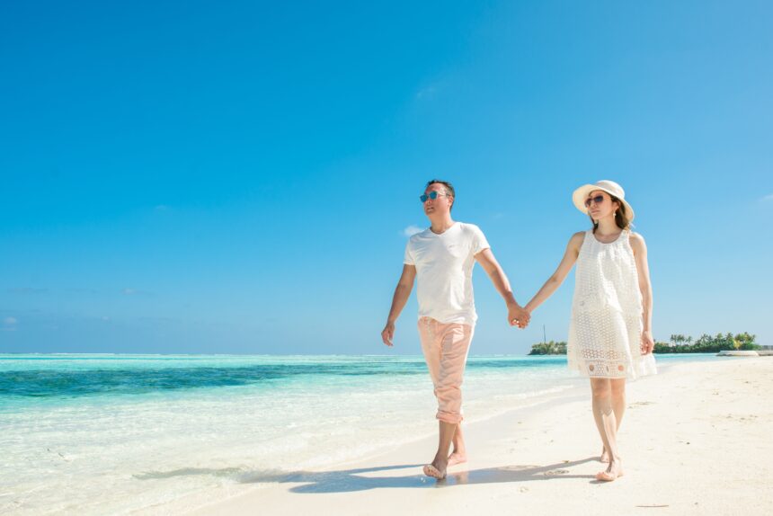 Couple walking hand in hand on a sandy beach during a romantic Philippines honeymoon